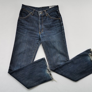 May include: Dark wash denim jeans with a classic five-pocket design. The jeans have a button and zip closure, and a slight flare at the hem. The denim has a worn look with some distressing at the bottom of the legs.