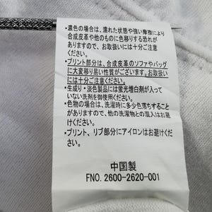 Pu&ograve; includere: Un'etichetta di tessuto bianco con testo giapponese e le parole "中国製" (Prodotto in Cina). L'etichetta include anche il numero "FNO. 2600-2620-001". &Egrave; visibile un ago d'argento.
