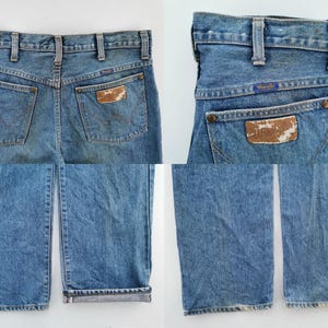 May include: Light blue denim jeans with a classic five-pocket design. The jeans feature a brown leather patch on the back pocket with the Wrangler logo. The jeans have a straight leg cut and a faded wash.