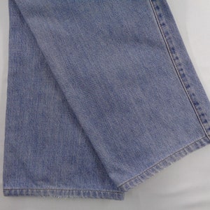 May include: Light blue denim jeans, folded and displayed. The fabric shows a classic denim texture with visible stitching along the seams. The jeans are a medium wash, suitable for casual wear.