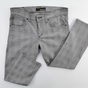 Puede incluir: Vaqueros grises a cuadros con un diseño clásico de cinco bolsillos. Los pantalones tienen cierre de botón y cremallera, trabillas para el cinturón y un pequeño bolsillo en la parte delantera. La etiqueta dice "REGULAR".
