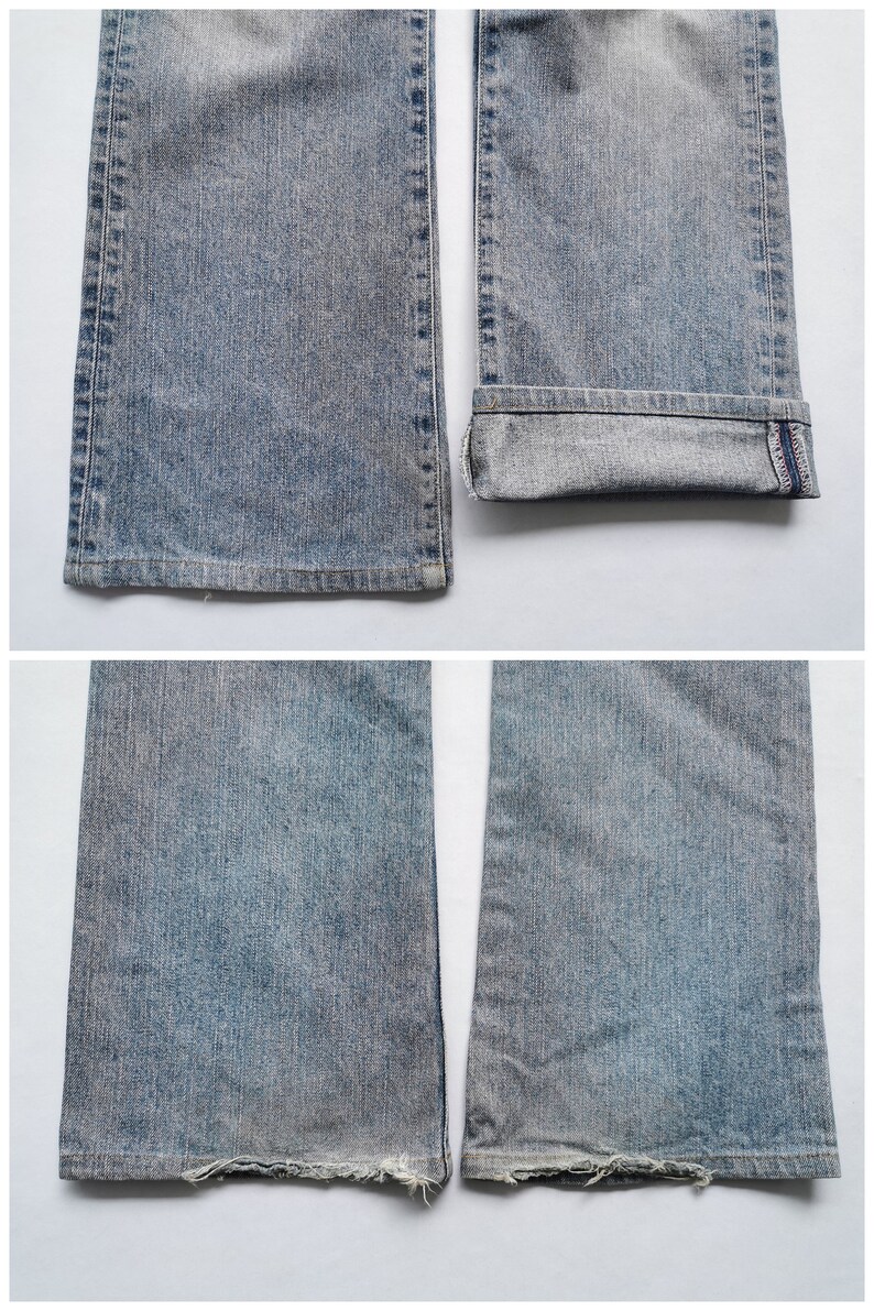 May include: Close-up of light blue denim jeans. The jeans have a faded wash and a slight flare at the bottom. One leg is cuffed, revealing a dark blue interior with red stitching. The other leg has a frayed hem.