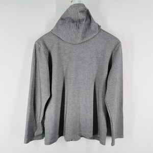 May include: A long-sleeved gray hooded sweatshirt featuring a textured knit fabric. The garment includes a hood at the neckline and long sleeves, with a straight hemline at the bottom. The overall design is simple, featuring a consistent gray color.