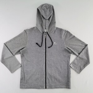 May include: A heather gray zip-up hoodie featuring long sleeves, a hood with black drawstring cords, and a full-length black front zipper. A small white graphic logo is printed on the upper left chest area of the garment.