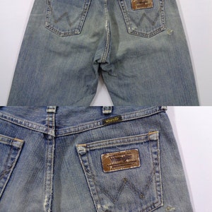Pu&ograve; includere: Jeans blu sbiaditi con il logo Wrangler sulle tasche posteriori. I jeans hanno un classico design a cinque tasche e un aspetto usurato. Le tasche posteriori presentano le iconiche cuciture "W" di Wrangler.