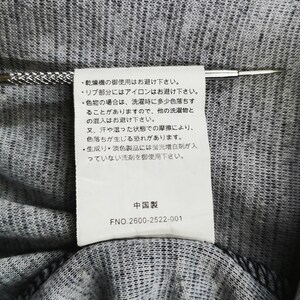 May include: Close-up of a tag with Japanese text and the text "Made in China" in black font. The tag is attached to a gray and black fabric. A silver pin is inserted through the tag.