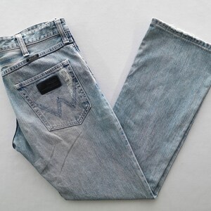 Pu&ograve; includere: Jeans in denim blu chiaro con un classico design a cinque tasche. Presenta una toppa in pelle nera sulla tasca posteriore con il logo del marchio. I jeans hanno un taglio dritto e un lavaggio sbiadito.