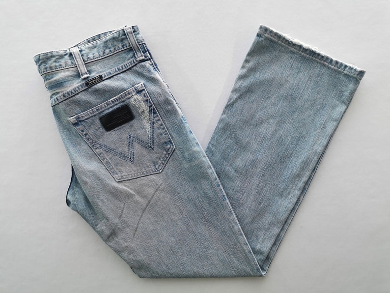 Pu&ograve; includere: Jeans in denim blu chiaro con un classico design a cinque tasche. Presenta una toppa in pelle nera sulla tasca posteriore con il logo del marchio. I jeans hanno un taglio dritto e un lavaggio sbiadito.