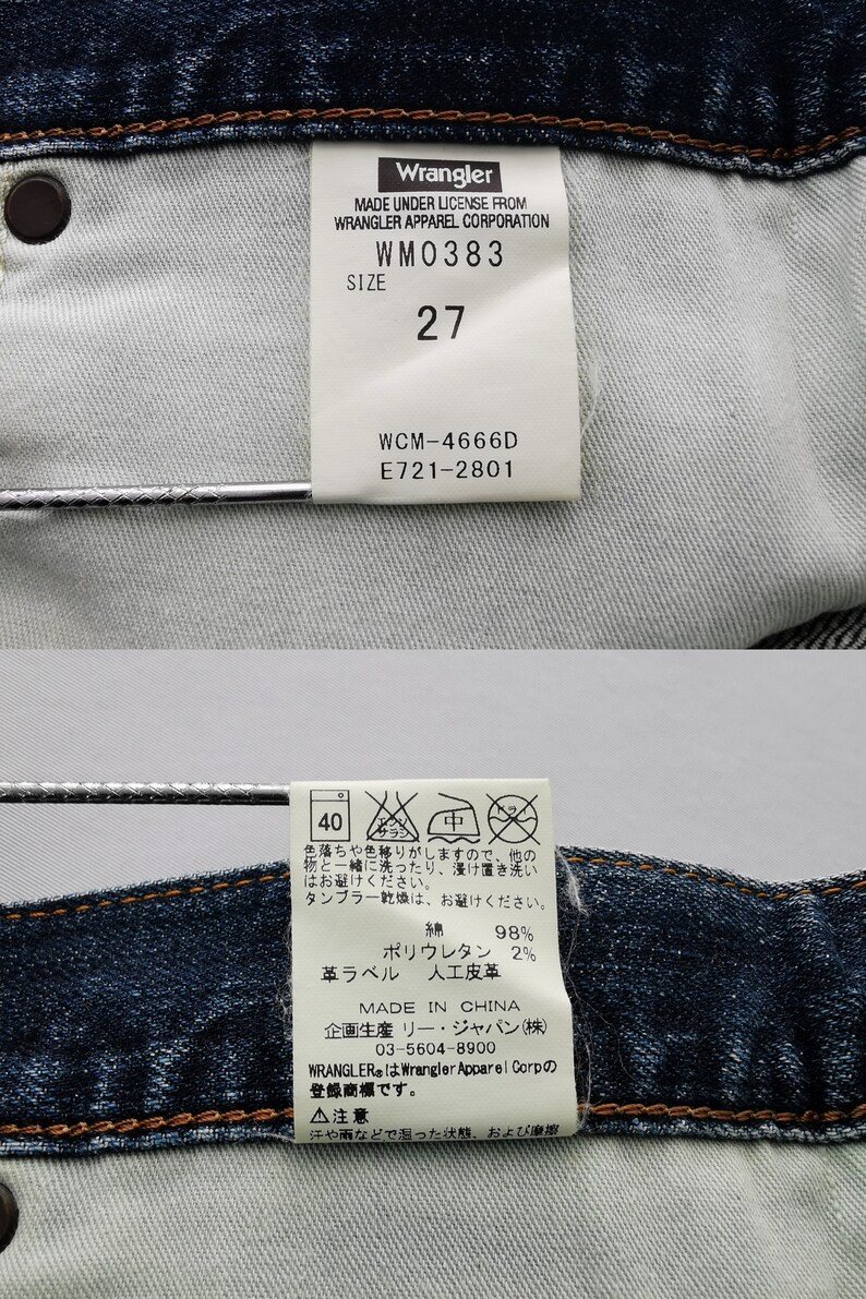 May include: Close-up of the inside of a pair of blue denim Wrangler jeans. The tags display the brand name, size 27, and care instructions. The fabric is a dark blue wash with visible stitching.