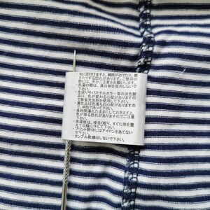 Puede incluir: Primer plano de una tela a rayas azul marino y blanca con una etiqueta de cuidado adjunta. La etiqueta contiene texto japon&eacute;s con instrucciones de cuidado. Un alfiler plateado se inserta a trav&eacute;s de la tela y la etiqueta.