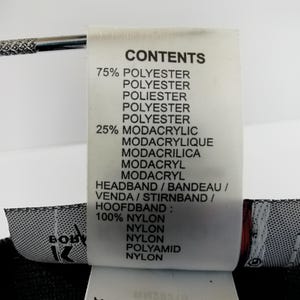 Puede incluir: Primer plano de una etiqueta blanca con texto negro que detalla la composici&oacute;n de una diadema. La etiqueta enumera materiales como poli&eacute;ster, modacr&iacute;lico y nailon. La palabra "HEADBAND" tambi&eacute;n est&aacute; escrita en varios idiomas.