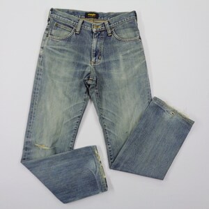 Pu&ograve; includere: Jeans in denim blu chiaro con un lavaggio sbiadito e un aspetto invecchiato. I jeans hanno un classico design a cinque tasche, una chiusura con bottone e cerniera e il logo Wrangler sulla tasca posteriore. I jeans presentano un piccolo strappo sul ginocchio sinistro.