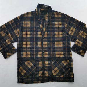 Puede incluir: Chaqueta a cuadros en tonos azul marino y marr&oacute;n. La chaqueta tiene cuello chal, dos bolsillos delanteros y tres botones. El estampado de cuadros es un dise&ntilde;o cl&aacute;sico, adecuado para uso informal. La chaqueta est&aacute; hecha de un material suave y c&aacute;lido.