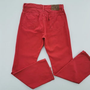 Op de afbeelding: Felrode denim jeans met een klassiek ontwerp met vijf zakken. De jeans hebben een rechte pijp en een leren merkpatch op de rug. Het merk Edwin is zichtbaar op de patch.