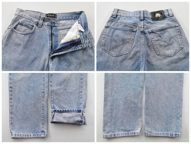 May include: Light blue denim jeans with a classic five-pocket design. The jeans feature a zip fly, belt loops, and a faded wash. The Versace logo is visible on the waistband and back patch. The jeans are cuffed at the hem.