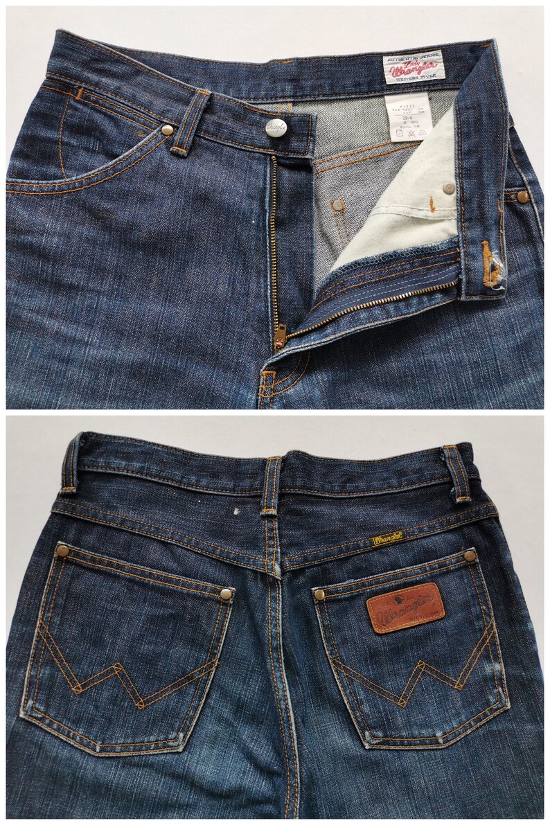 May include: Dark wash denim Wrangler jeans. The jeans have a classic five-pocket design with a zip fly and button closure. The back pockets feature the signature Wrangler stitching and a leather patch with the Wrangler logo.
