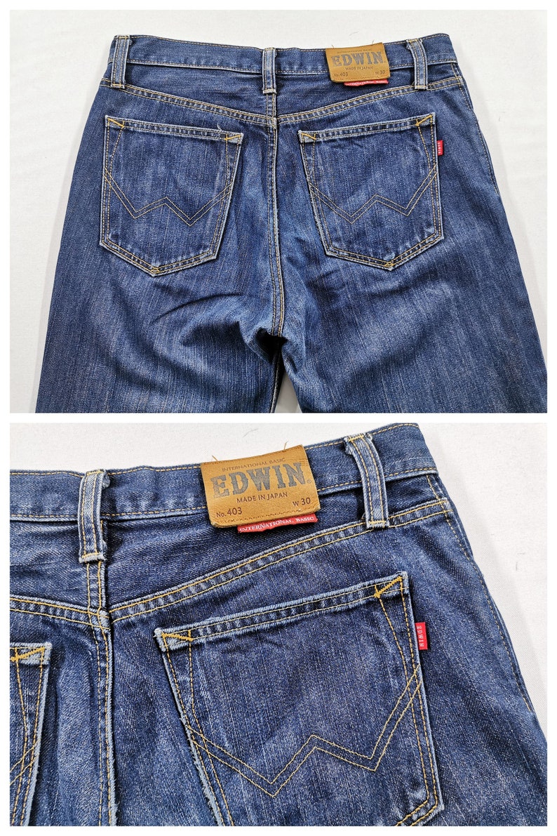 May include: Close-up of the back of blue denim jeans. The jeans have two back pockets with a distinctive W-shaped stitch design. A brown leather patch with the brand name "EDWIN" is visible at the waistband.