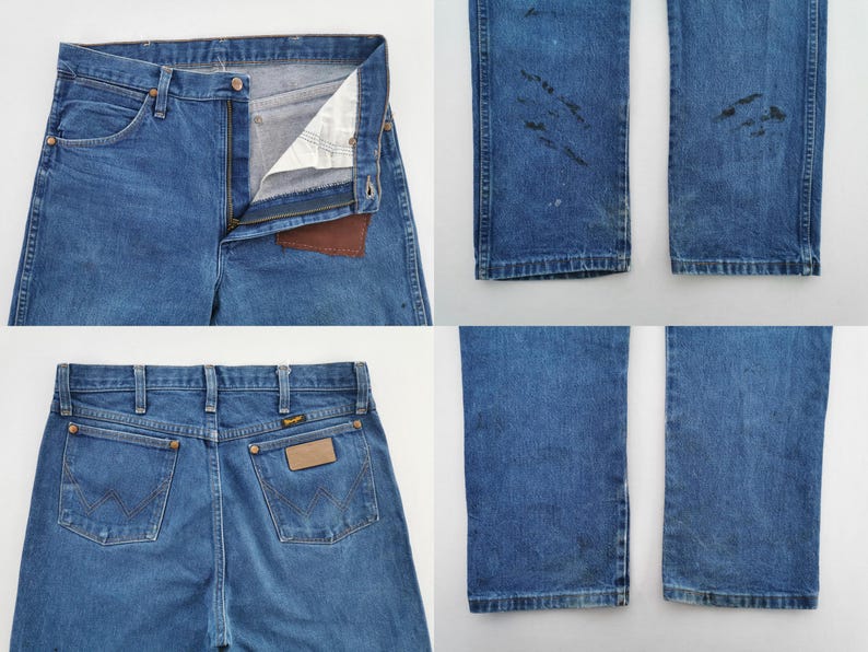May include: Blue denim jeans featuring a front zipper closure, a brown leather patch on the interior waistband, and two back pockets with a stitched W design. The legs show dark distressed markings and wear patterns on the lower sections.