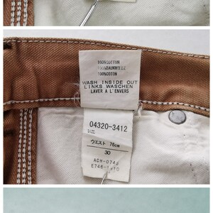 May include: Close-up of Carhartt brown canvas double knee pants. The tag indicates a 30x34 size, with a 76cm waist. The label also includes washing instructions and the text "Made in China."