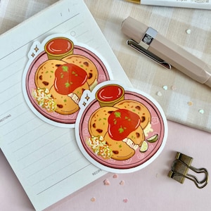 May include: Two stickers of a Salvadoran dish called pupusas. The pupusas are on a pink plate with a side of curtido, a white sauce, and a lime wedge. The stickers are on a pink background with white hearts.