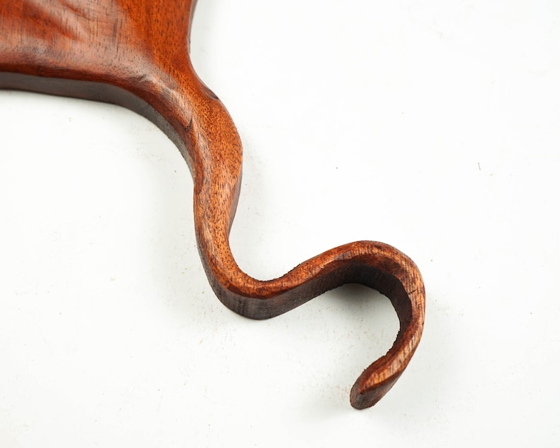 Op de afbeelding: Een houten carving van een vogelkop en -nek, met een gebogen nek en een gedetailleerde snavel. De carving is een rijke bruine kleur en heeft een gladde, gepolijste afwerking.