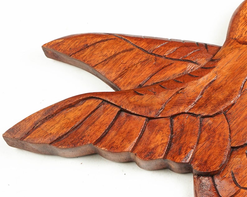 May include: A wooden carving of a bird with detailed wings. The bird is made of dark brown wood and has a natural finish.