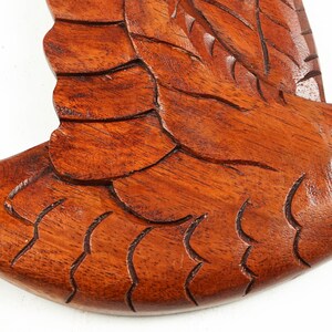 May include: A wooden carving of a bird in flight, with detailed feathers and a rich brown color.