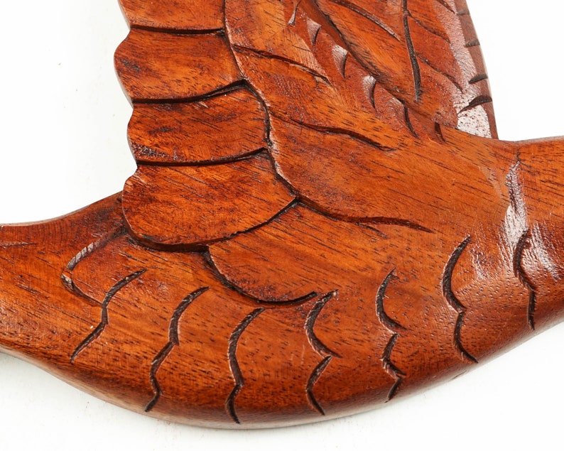May include: A wooden carving of a bird in flight, with detailed feathers and a rich brown color.