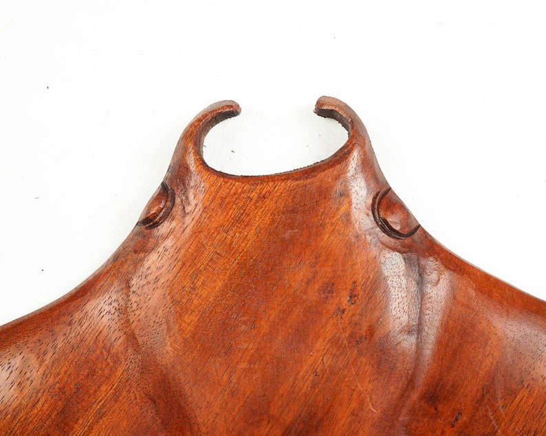 Op de afbeelding: Een houten beeldhouwwerk van een mantarog, met een roodbruine kleur en een gladde, gepolijste afwerking. Het beeldhouwwerk is gedetailleerd met de ogen en kieuwen van de mantarog.