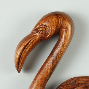 Pu&ograve; includere: Una scultura in legno della testa e del collo di un fenicottero. La scultura &egrave; di un ricco colore marrone e presenta un design dettagliato.