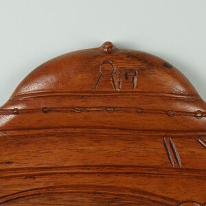 Peut inclure: Une sculpture en bois d'une structure en forme de d&ocirc;me avec un motif sculpt&eacute; de trois personnages au sommet. La sculpture est d'une couleur brun fonc&eacute; et a une finition lisse et polie.