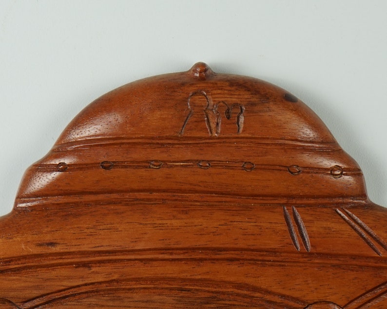 Peut inclure: Une sculpture en bois d'une structure en forme de d&ocirc;me avec un motif sculpt&eacute; de trois personnages au sommet. La sculpture est d'une couleur brun fonc&eacute; et a une finition lisse et polie.