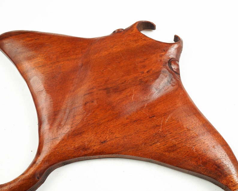 Op de afbeelding: Een handgesneden houten sculptuur van een mantarog. Het beeld is gemaakt van een rijk, roodbruin hout en heeft een gladde, gepolijste afwerking.