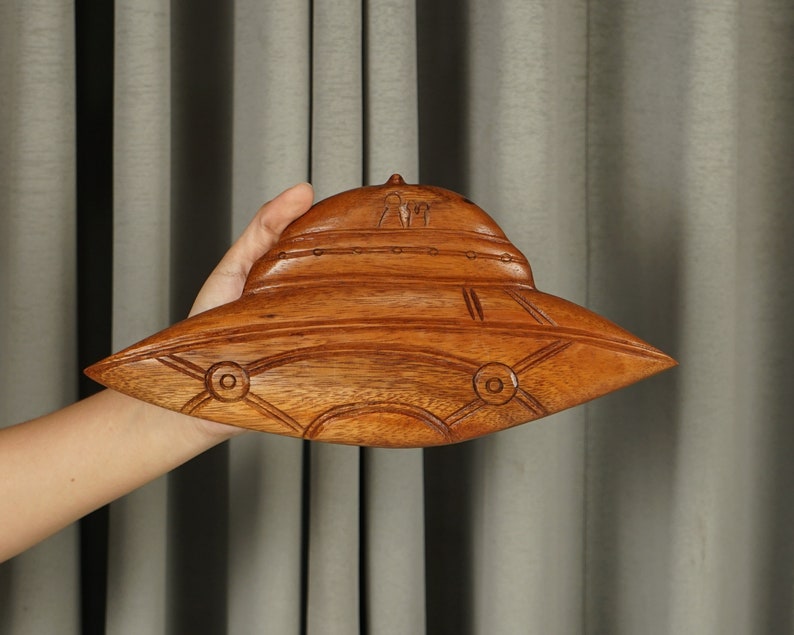 Peut inclure: Une sculpture en bois d'une soucoupe volante, avec des d&eacute;tails complexes et une finition en bois brun.
