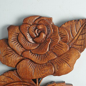 May include: A carved wooden rose with detailed leaves. The rose is a rich brown color and has a realistic appearance.