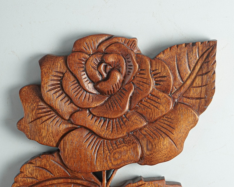 May include: A carved wooden rose with detailed leaves. The rose is a rich brown color and has a realistic appearance.