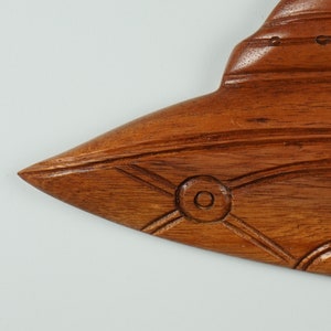 Peut inclure: Une sculpture en bois d'un poisson avec des d&eacute;tails complexes. Le poisson est brun et a un &oelig;il sculpt&eacute;. La sculpture est une d&eacute;coration murale.