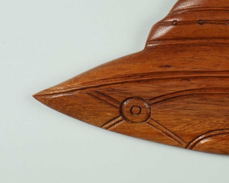 Peut inclure: Une sculpture en bois d'un poisson avec des d&eacute;tails complexes. Le poisson est brun et a un &oelig;il sculpt&eacute;. La sculpture est une d&eacute;coration murale.