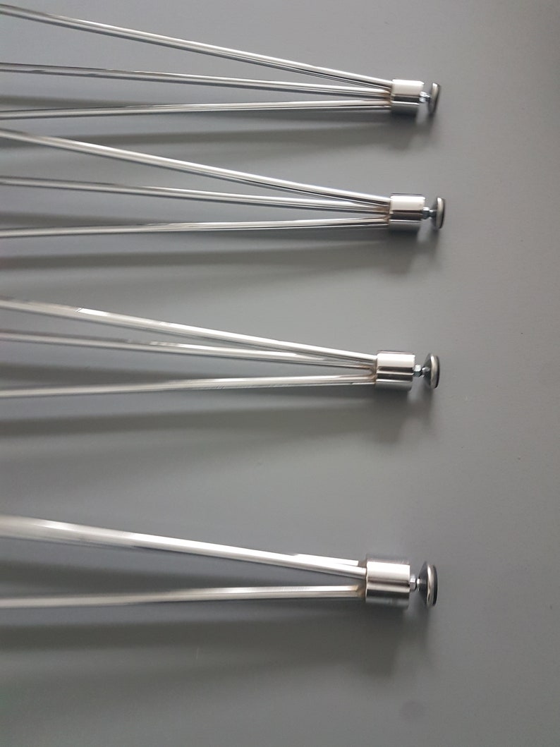 May include: Four stainless steel bicycle wheel spokes, each with multiple thin, silver rods radiating from a central hub. The spokes are arranged diagonally against a gray background, showcasing their design and construction.
