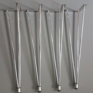 May include: Set of four shiny, silver hairpin legs for furniture. Each leg has a rectangular mounting plate and a sleek, tapered design. The legs are made of metal and are suitable for various DIY projects.