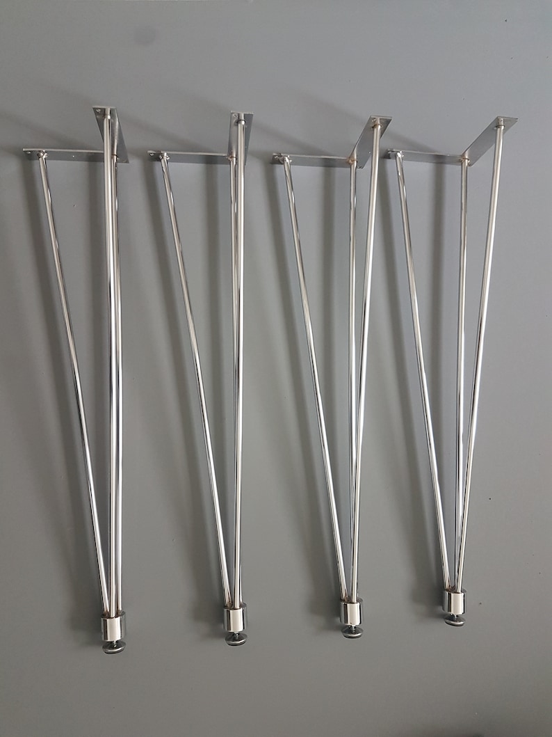 May include: Set of four shiny, silver hairpin legs for furniture. Each leg has a rectangular mounting plate and a sleek, tapered design. The legs are made of metal and are suitable for various DIY projects.