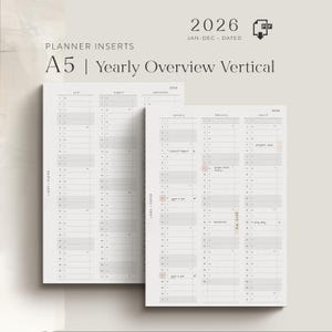 May include: Two A5 yearly overview vertical planner inserts for 2026. The inserts are white with a grid layout and include the months of the year. The text "LINES + PAPER" is printed vertically on the left side of the inserts.