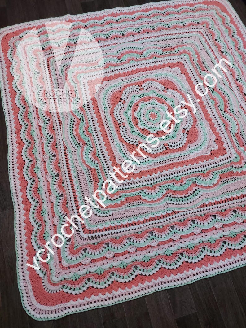 K&ouml;nnte beinhalten: Eine geh&auml;kelte Babydecke in den Farben Rosa, Wei&szlig; und Gr&uuml;n. Die Decke hat ein quadratisches Design mit mehreren Schichten aus komplizierten H&auml;kelmaschen.