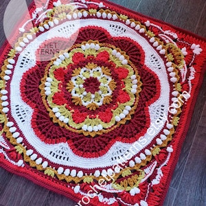 Op de afbeelding: Een vierkant, handgemaakt gehaakt kleed met een cirkelvormig mandala-ontwerp. Het kleed gebruikt rood, wit en goud garen, met ingewikkelde patronen en texturen. De tekst "Crochet Patterns" en "vcrochetpatterns.com" zijn zichtbaar.