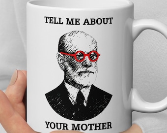 May include: White ceramic mug with a black and white illustration of a man wearing red glasses. The text "TELL ME ABOUT YOUR MOTHER" is printed on the mug.