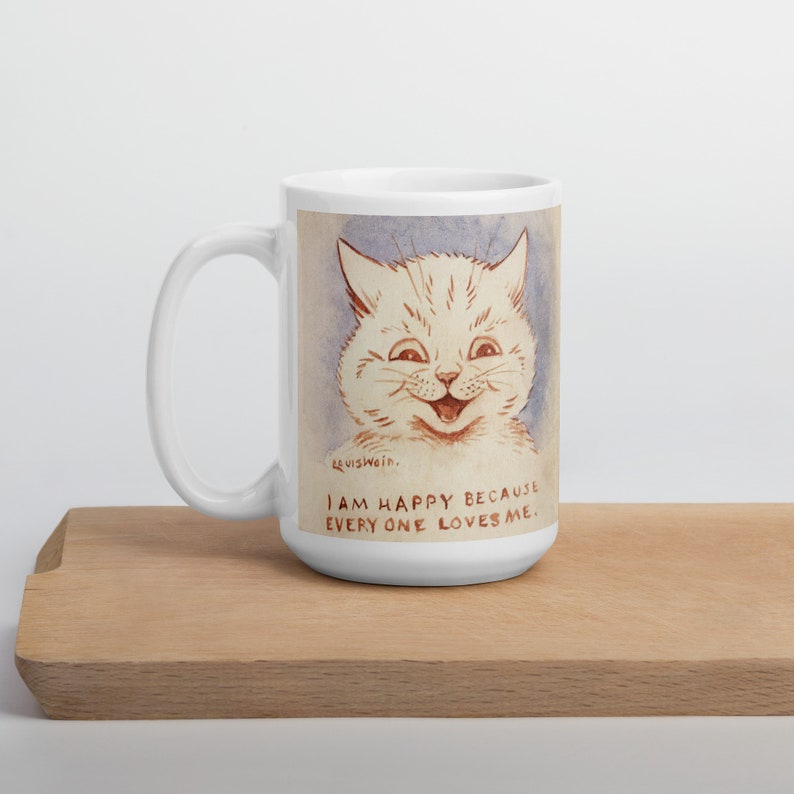 Pu&ograve; includere: Tazza in ceramica bianca con un'illustrazione di un gatto bianco con un grande sorriso. Il testo sulla tazza dice "Sono felice perch&eacute; tutti mi amano."