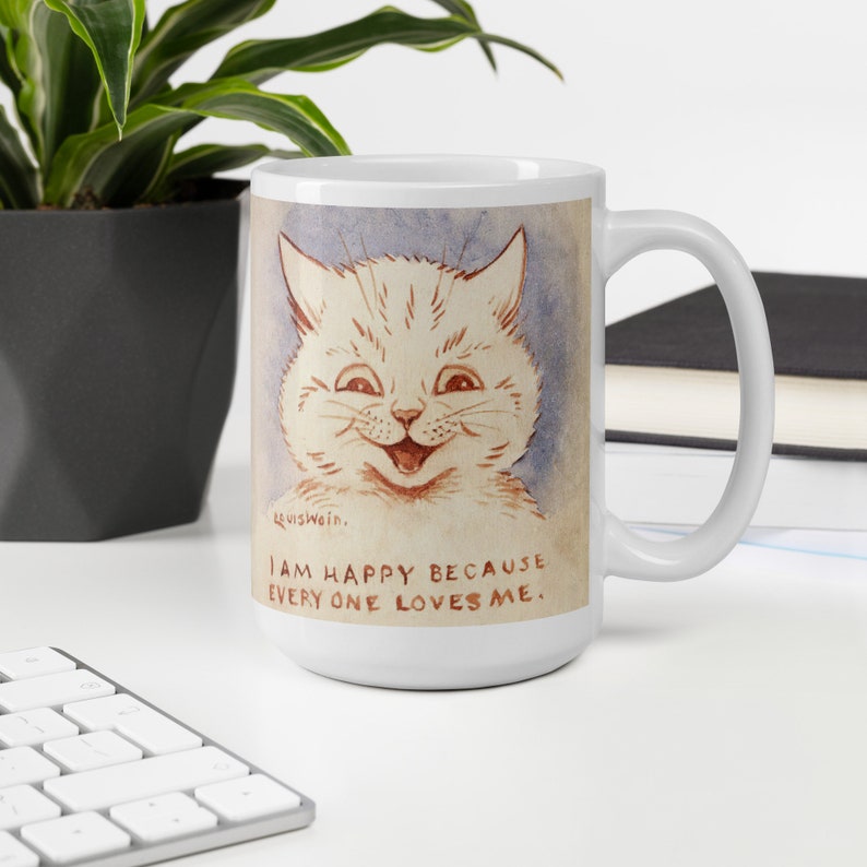 Pu&ograve; includere: Tazza in ceramica bianca con un'illustrazione di un gatto sorridente in stile cartone animato. Il testo sulla tazza recita "Sono felice perch&eacute; tutti mi amano."