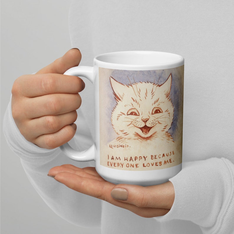 Pu&ograve; includere: Tazza in ceramica bianca con un'illustrazione di un gatto sorridente in stile cartone animato. Il testo sulla tazza recita "Sono felice perch&eacute; tutti mi amano."