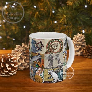 May include: White ceramic mug featuring a medieval-style illustration of cats, owls, and figures reading books. The design includes a variety of colors and patterns. The mug has a white handle and the text "MattCollins Designs".