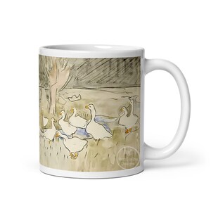 May include: White ceramic coffee mug with a watercolor illustration of a group of geese in a pond. The geese are white with orange beaks and feet. The background is a light brown with a dark brown tree in the background. The mug has the text "Matt Collins Designs" on the bottom.
